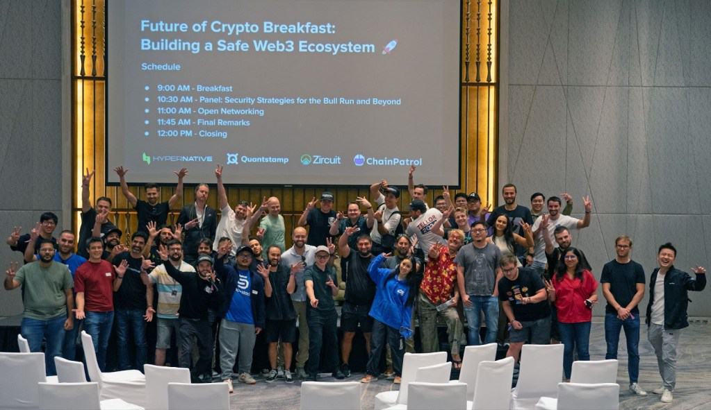 a group of people standing in front of a screen, waving at the camera. the screen reads, "future of crypto breakfast"